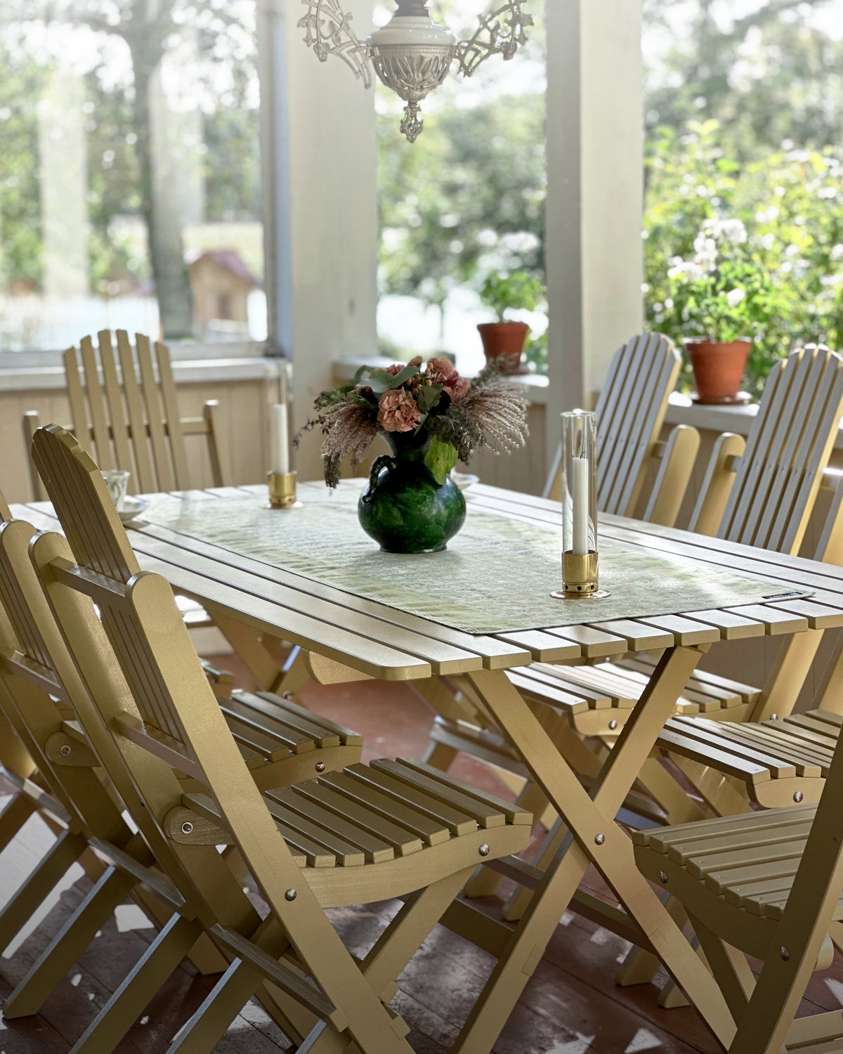 Trädgårdsmöbler placerade på veranda med stort trädgårdsbord i jugendgul färg för utomhusbruk.