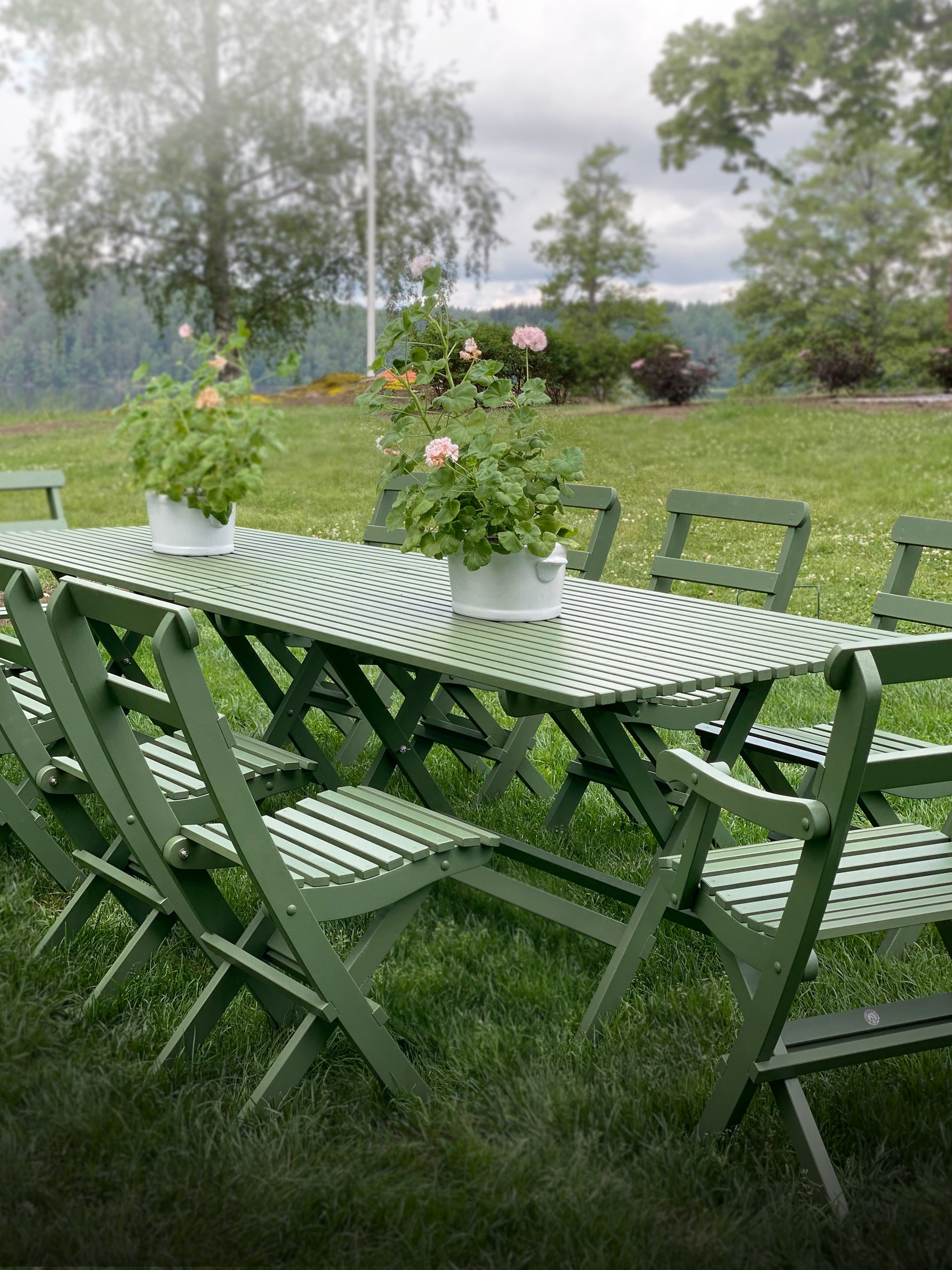 Gröna hopfällbara trädgårdsmöbler i trä – långt bord med stolar, klassiska utemöbler i sekelskiftesstil för trädgård eller veranda.