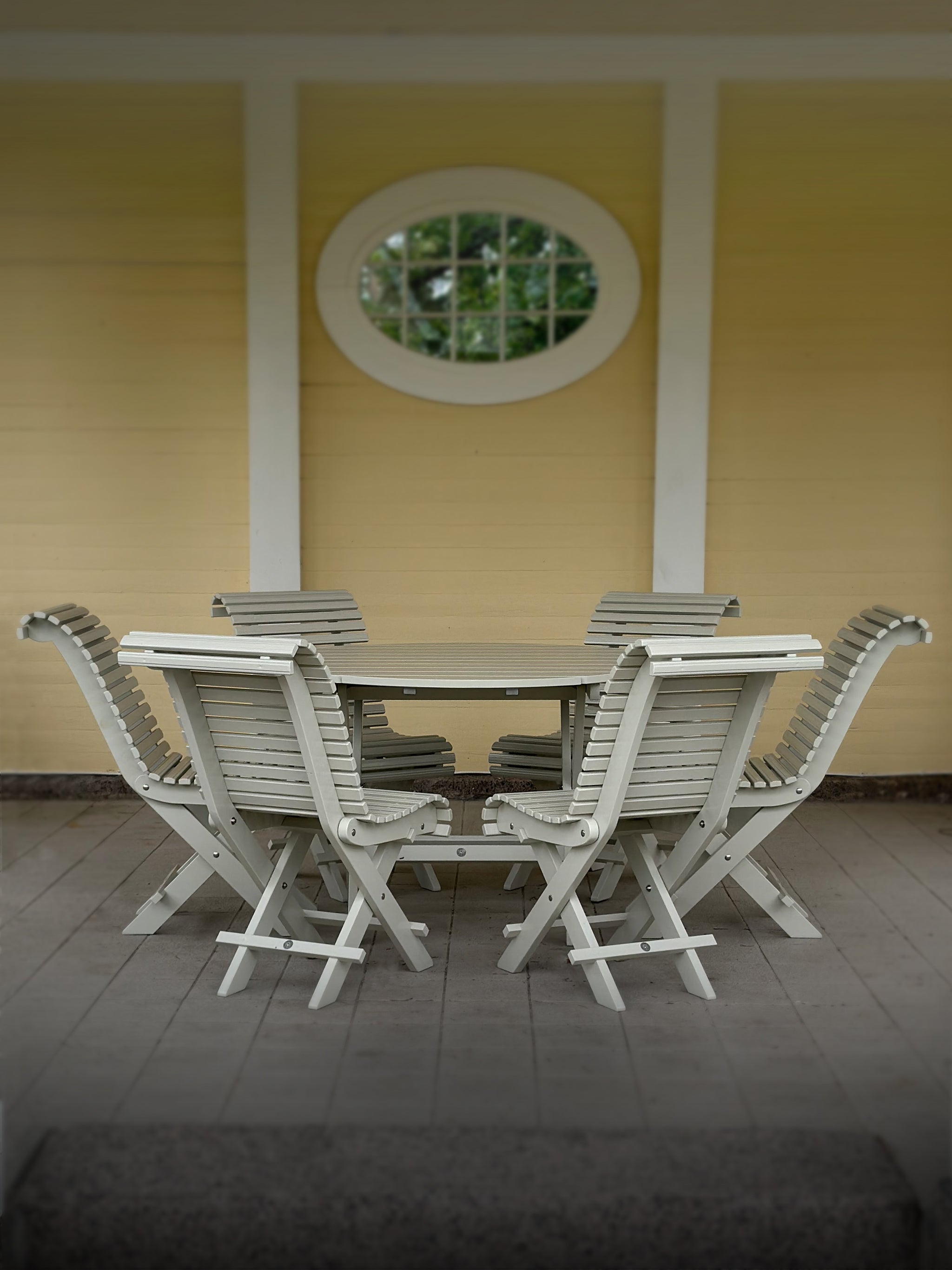 Gray foldable wooden garden furniture – Classic Garden Table with matching chairs, placed against a yellow facade.