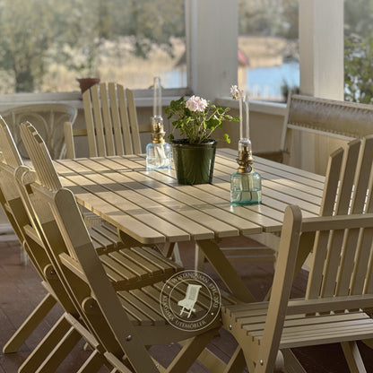 Wooden outdoor dining table with chairs on a deck with a scenic view.